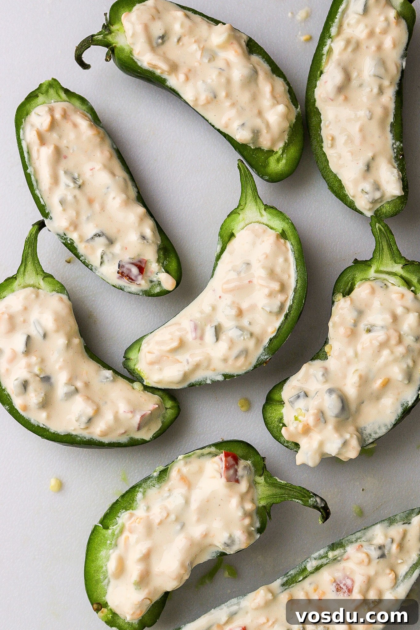 Top down view of jalapeno peppers cut in half with queso dip stuffed into ready for the air fryer.