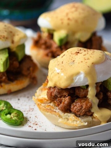 Three eggs benedicts on a plate with hollandaise sauce dripping down.