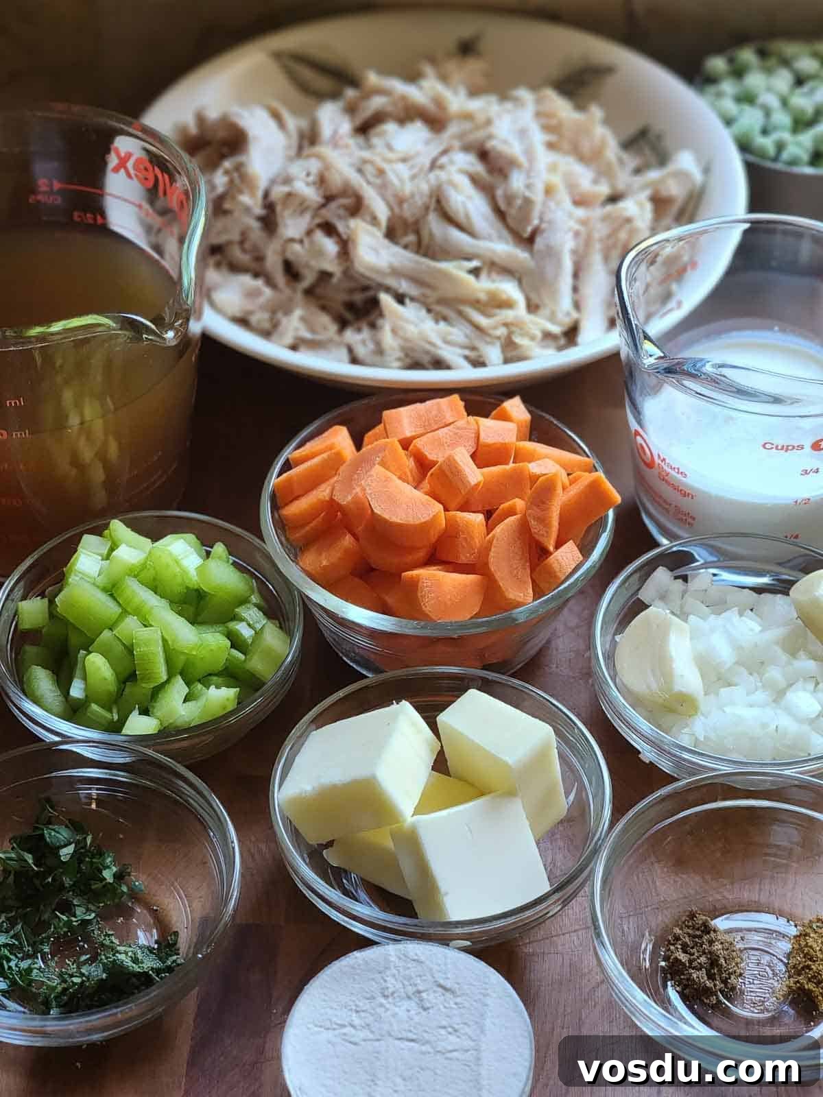 Ingredients for chicken pot pie filling in little bowls on a wood surface.