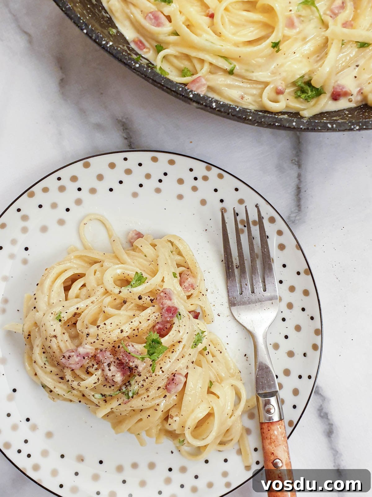A plate of spaghetti carbonara sprinkled with black pepper.