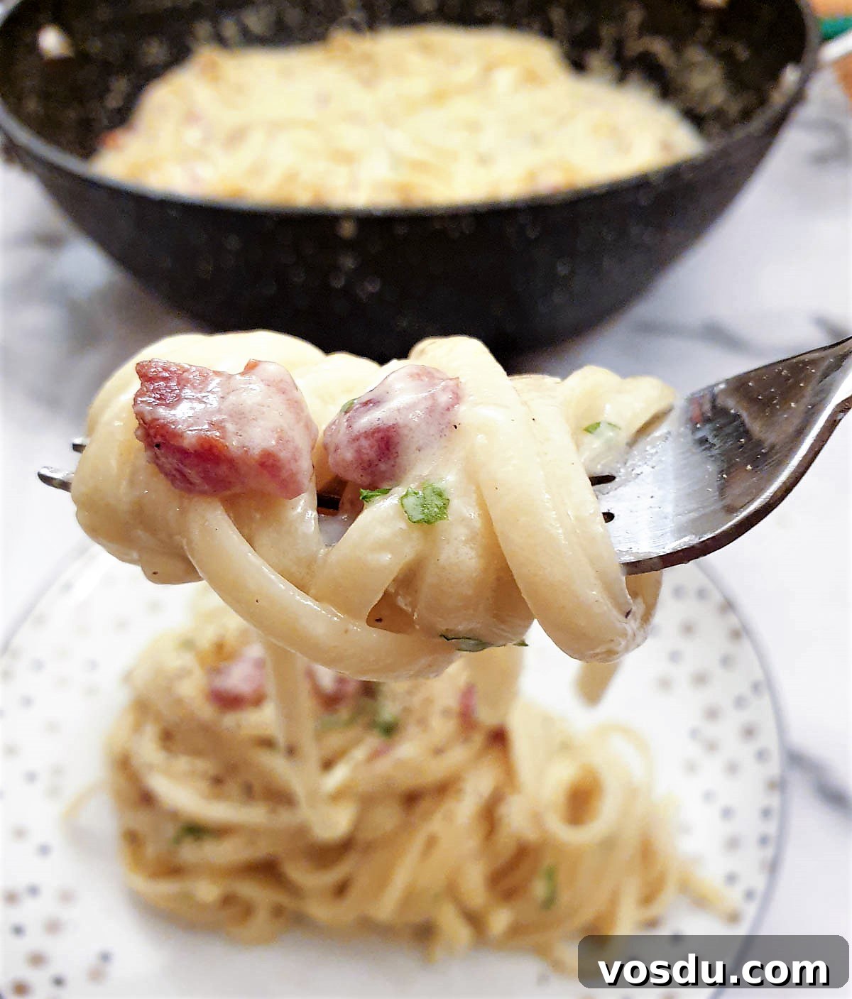 A close up of spaghetti carbonara wrapped around a fork.
