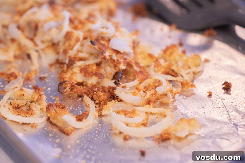 Fried onions stacked on aluminum foil.
