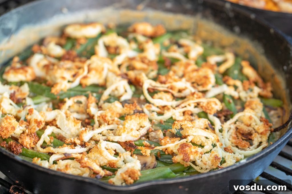 Green bean casserole in a cast iron skillet on the grill grates of a smoker.