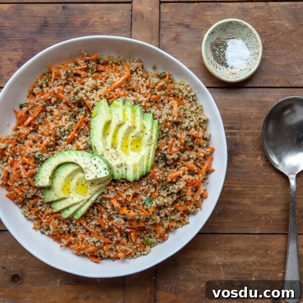 Sesame-Honey Quinoa and Carrot Salad in white bowl, topped with Sliced Avocado.