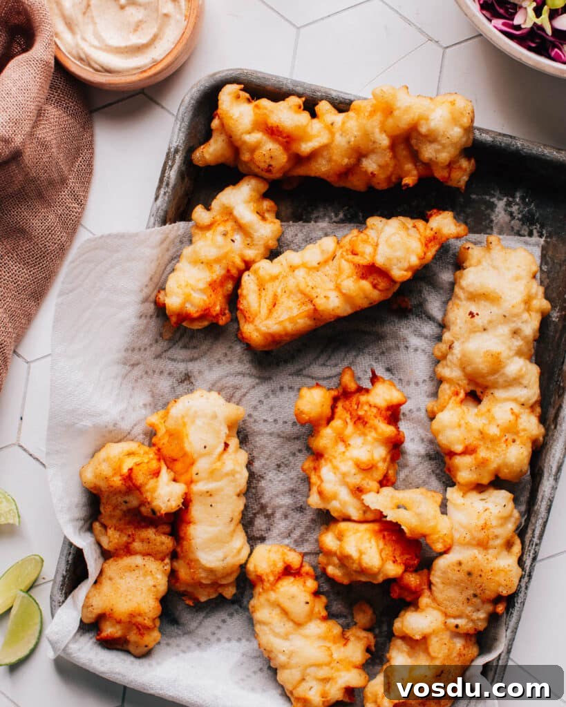 Fried Baja fish for tacos on a paper towel-lined plate.