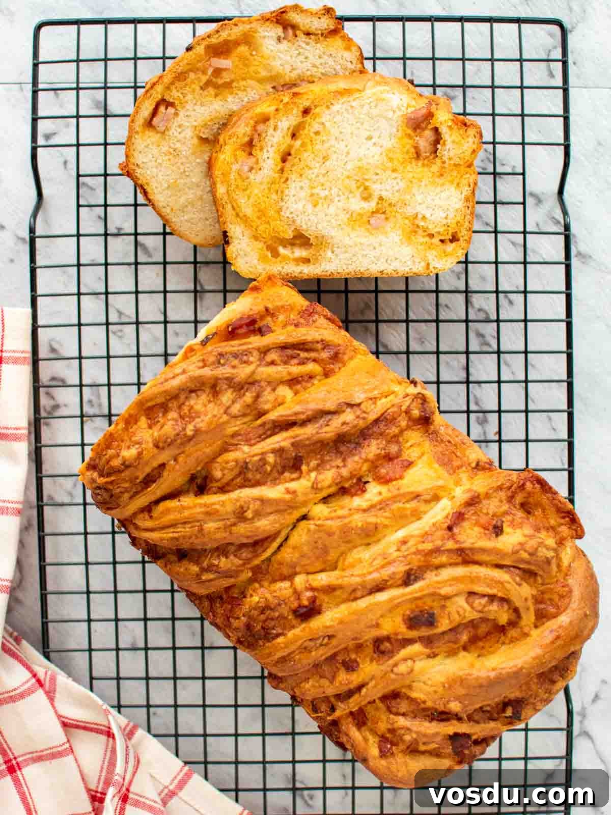 Bacon cheese bread on black wire rack with two slices cut viewed from above.
