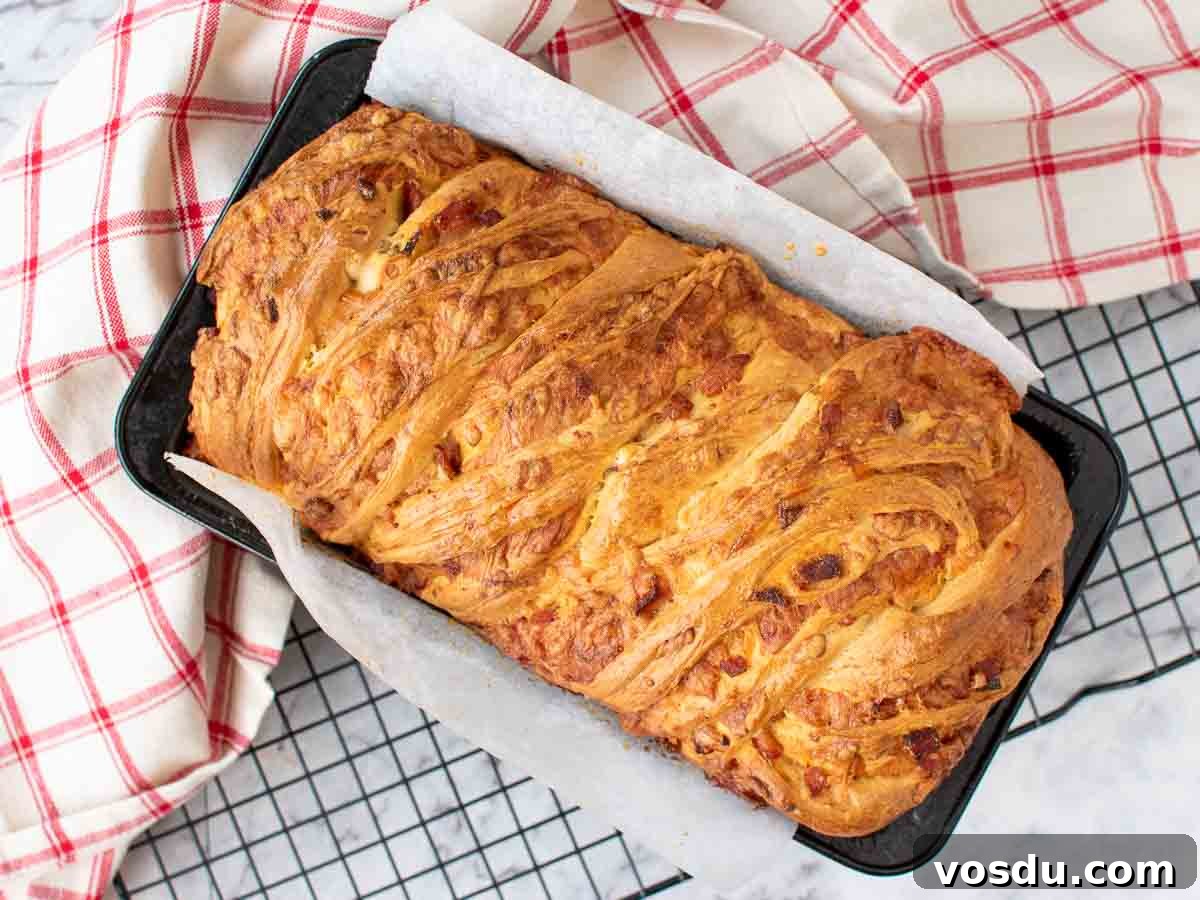 Bread loaf in pan on black wire with red and white cloth rack viewed from above.