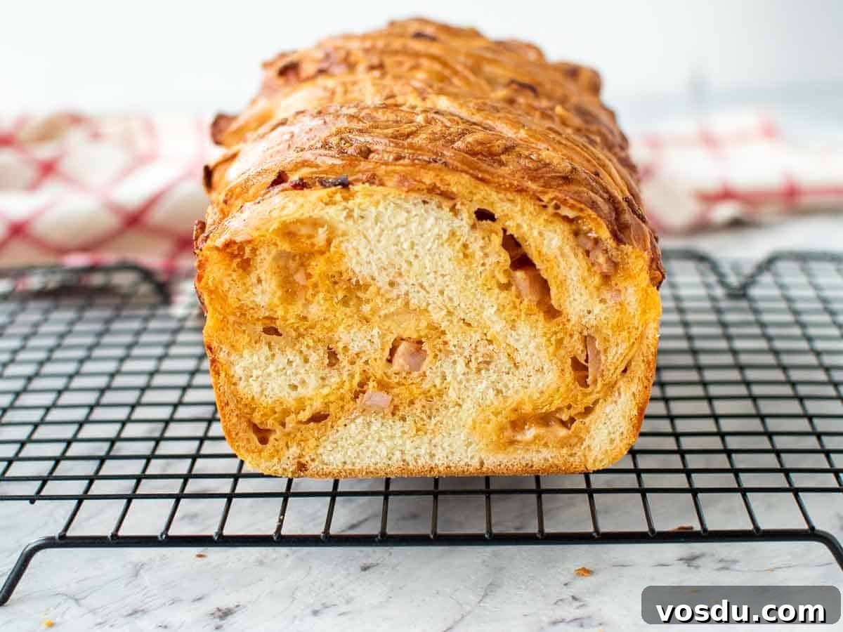 Cross section of cheese filled Bread loaf on black wire rack.