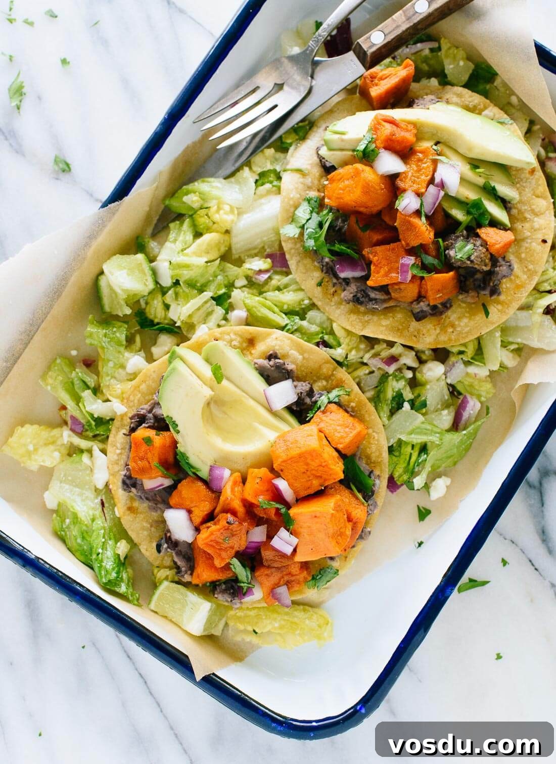This vegetarian tostadas recipe features roasted sweet potatoes and healthy "refried" black beans, served on a crisp salad. Gluten free and easily vegan!