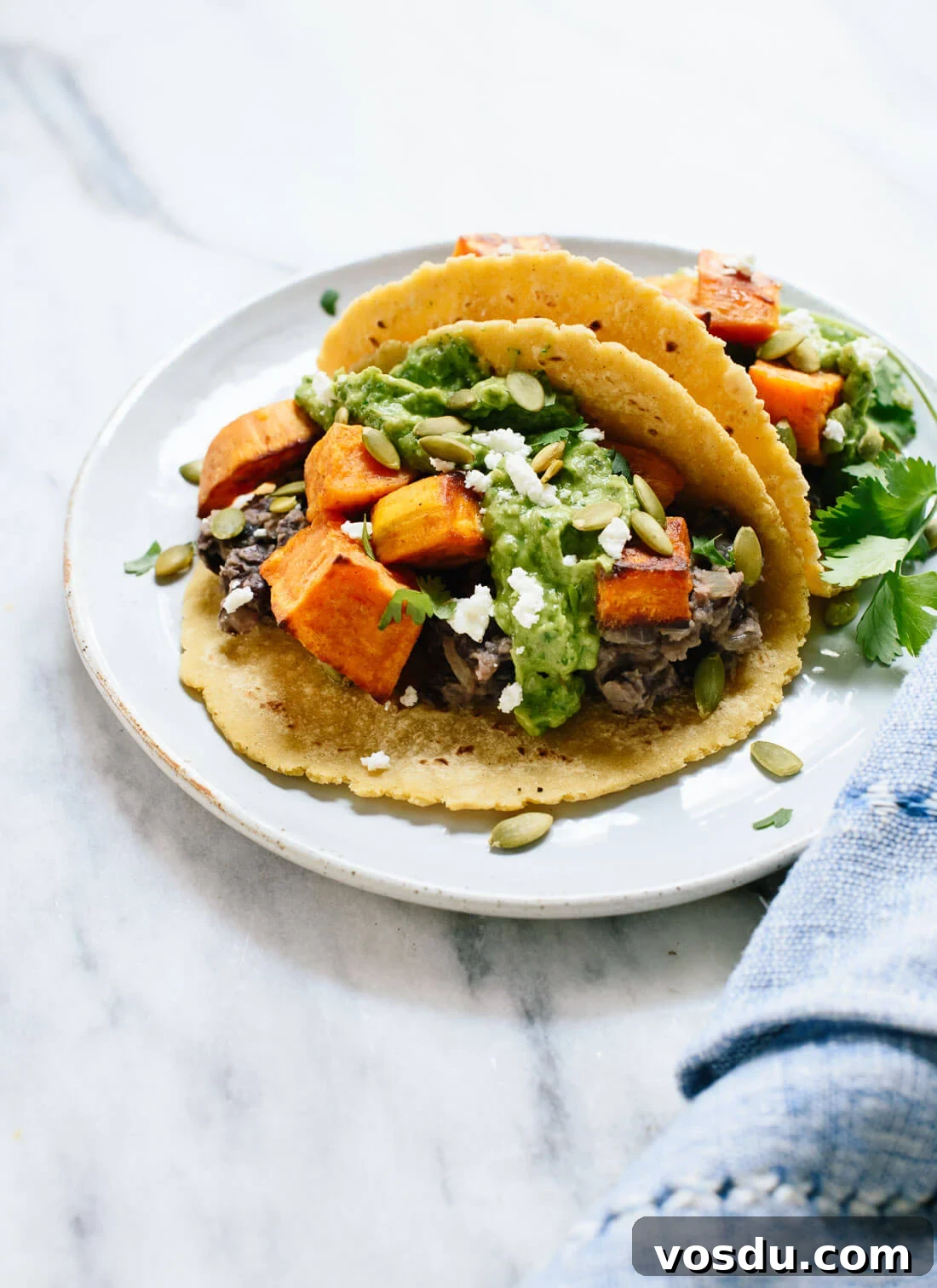 These roasted sweet potato tacos feature spicy black beans and avocado-pepita dip. Delicious! This taco recipe is vegetarian (easily vegan) and gluten-free. cookieandkate.com