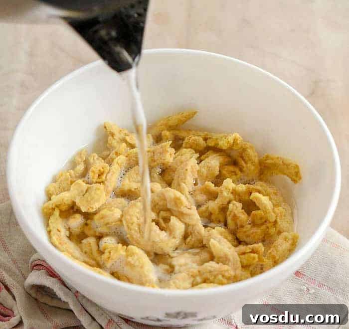 Hot water being poureed over soy curls in white bowl.