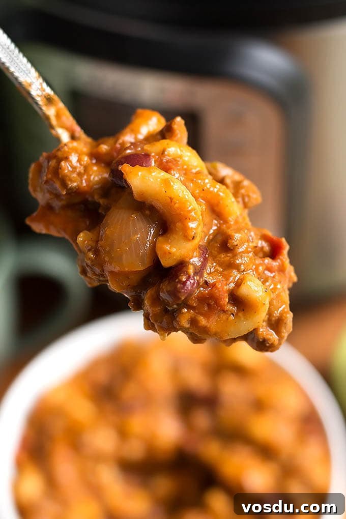 Close up of spoonful of Chili Mac above a white bowl