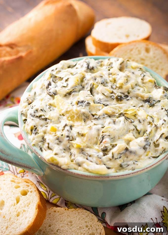 Spinach Artichoke Dip in a turquoise bowl next to slices of bread