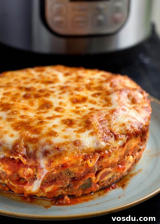 Round Lasagna on a light blue plate in front of pressure cooker