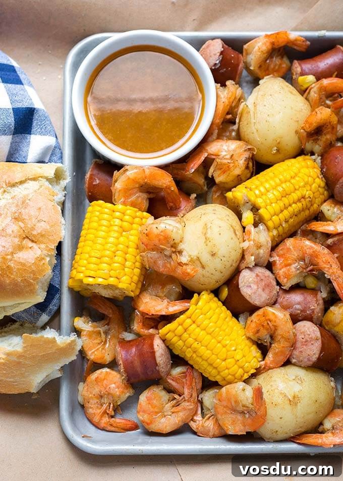 Low Country Shrimp Boil on a baking sheet with small white bowl of brown sauce