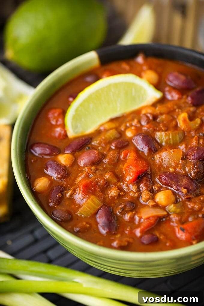 Chili in a green bowl next to green onion and limes