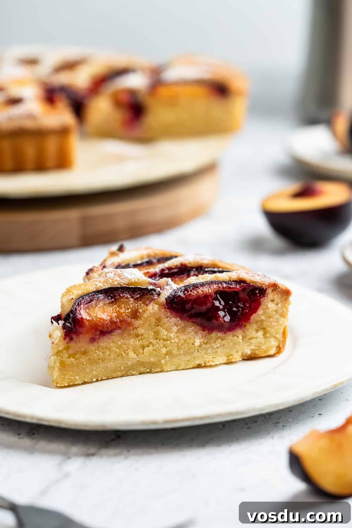 A slice of plum almond tart on a dessert plate.