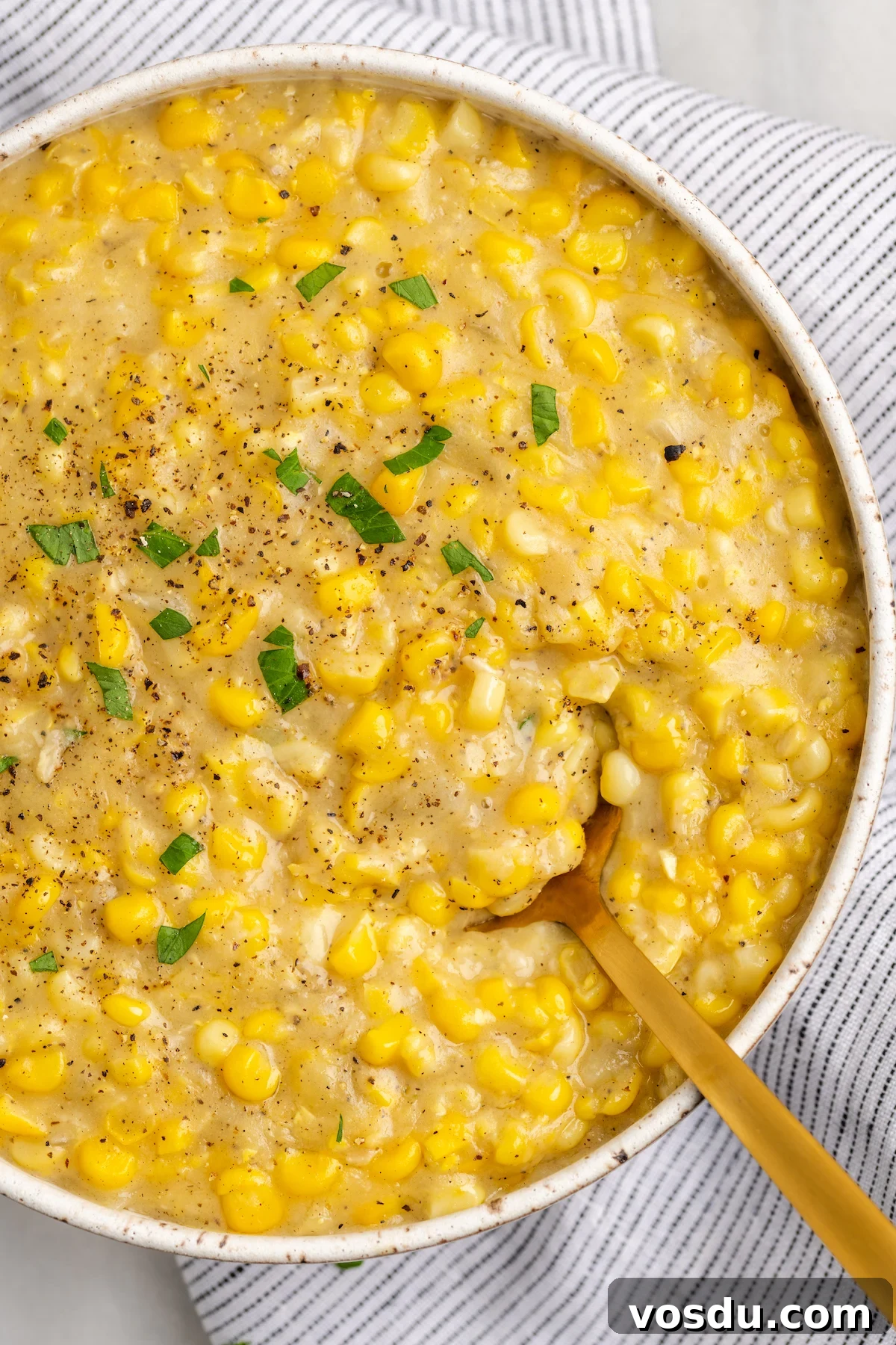 Overhead view of vegan creamed corn in serving bowl with gold spoon