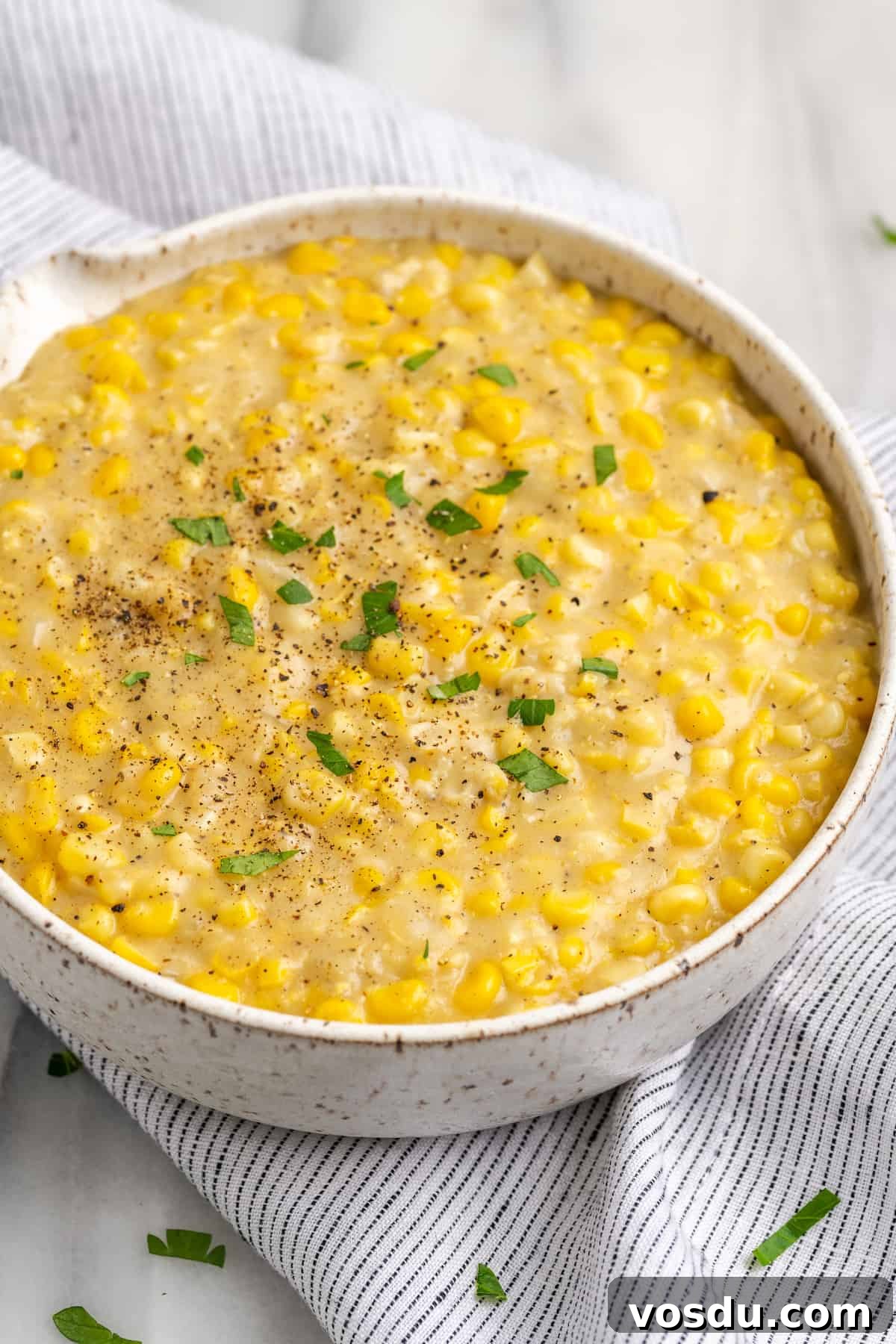 Serving bowl of vegan creamed corn on striped linen