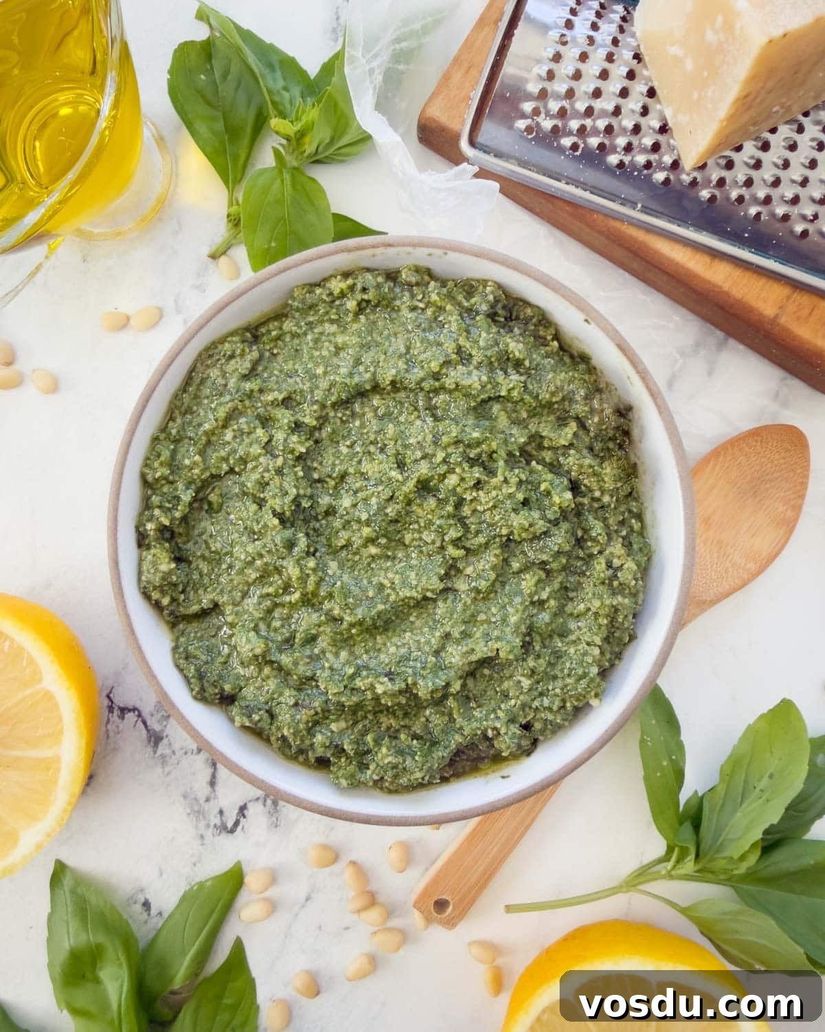 A bowl pf pesto alla Genovese, or basil pesto, with basil leaves, oil, lemons, and parmesan.