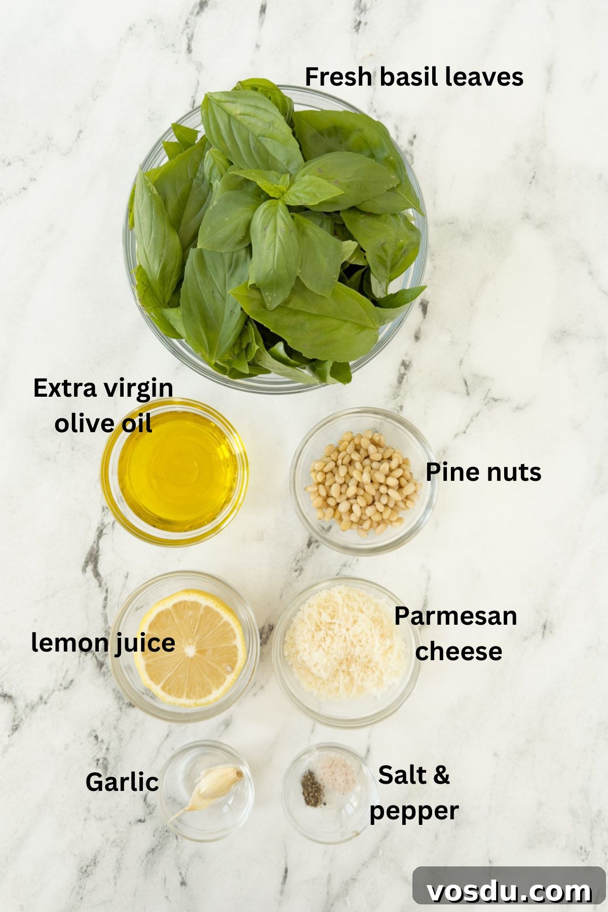 Ingredients for basil pesto (pesto alla Genovese) on a counter in glass prep bowls.