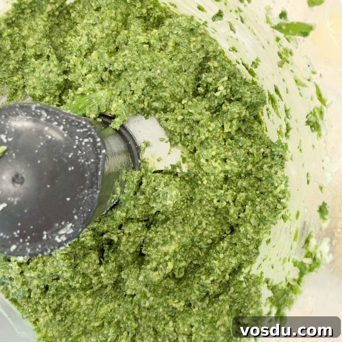 Bright green basil pesto in a food procesor workbowl.
