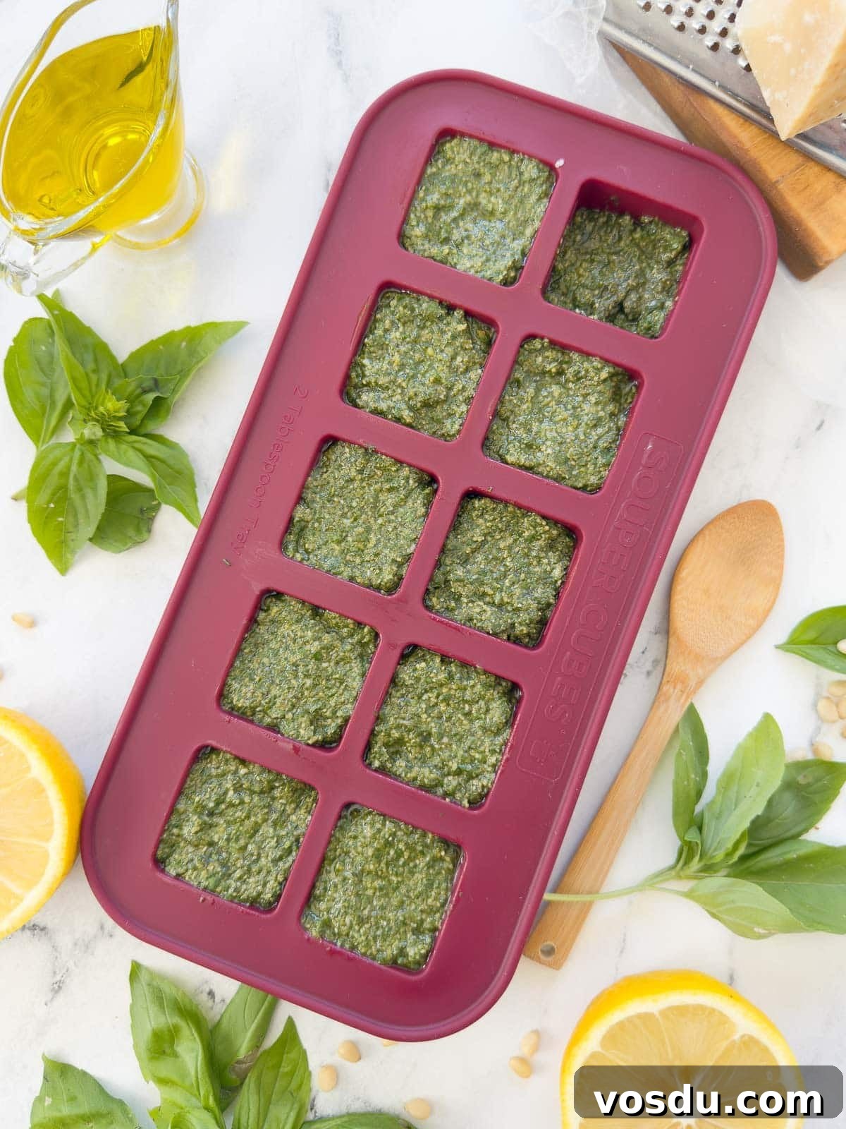 Bright green basil pesto in a cranberry Souper Cubes tray for freezing.